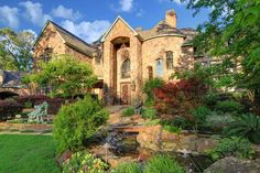 a large brick house surrounded by lush green grass and trees, with a pond in the front yard