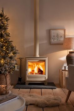 a living room with a christmas tree in the corner and a fire place on the floor