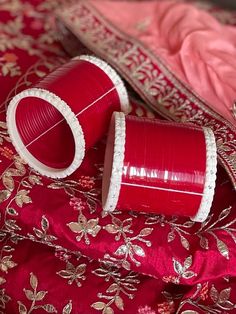 two red vases sitting on top of a bed next to a pink comforter