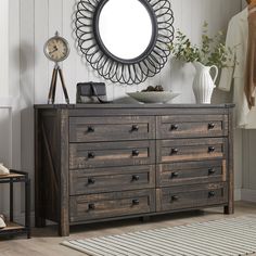 a dresser with drawers and a mirror on the wall above it in a white room