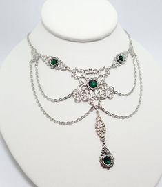 This is a new handmade necklace. It is made with light weight silver plated filigrees, accented with high quality EMERALD GREEN glass rhinestones and adorned with draping chains. Decorated portion is 5 1/2" wide and 3 1/4" tall in the center. Necklace is adjustable 15-18" with a lobster clasp and chain extender. If you would like a different length, please send us a message.Matching earrings and headpiece are listed in our store, also in a variety of other colors. Silver Gothic Necklaces For Fantasy Events, Adjustable Silver Fantasy Choker, Silver Fantasy Choker Adjustable, Silver Fantasy Body Jewelry For Gift, Silver Gothic Jewelry For Fantasy Events, Silver Necklace For Fantasy Events, Silver Fantasy Jewelry For Festivals, Silver Fantasy Choker Necklace, Gothic Nickel-free Silver Body Jewelry