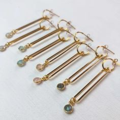 Long, elegant dangle earrings just in time for spring. These gorgeous earrings are made with an 18k gold-plated brass long loop on a small post hoop. A delicate gemstone bezeled in gold vermeil dangles at the bottom. Choose from eight colors.18k gold-plated brass 2.25" lengthGreen chalcedony, labradorite, rose quartz, pyrite, ruby, sapphire, black spinel, or moonstoneHandmade in CaliforniaShips in 3-5 business daysThis item qualifies for free shipping! Luxury Gold Gemstone Danglers, Gold Dangle Gemstone Linear Earrings, Gold Gemstone Dangle Hoop Earrings, Gold Dangle Hoop Earrings With Gemstone, Gold Long Drop Chandelier Earrings With Gemstones, Green Chalcedony, Gold Dangle Earrings, Ruby Sapphire, Black Spinel