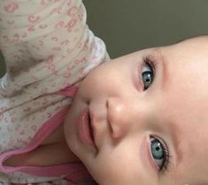 a close up of a baby laying on the ground with its eyes wide open and looking at the camera