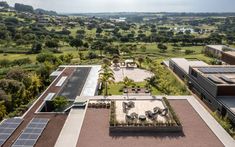 an aerial view of a building with solar panels on the roof and landscaping around it