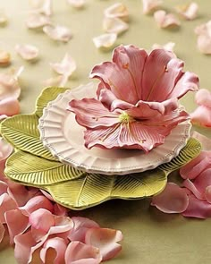 two paper plates with pink flowers on them and petals scattered all over the table top