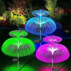 three umbrellas that are lit up in the grass at night with lights on them