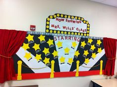 a classroom wall decorated with red curtains and yellow stars on the front, and a sign that says now showing mrs willis class starting