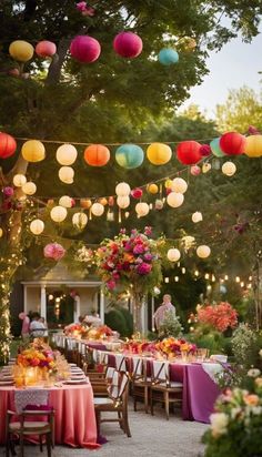 an outdoor party with paper lanterns strung from the ceiling and tables covered in pink tablecloths