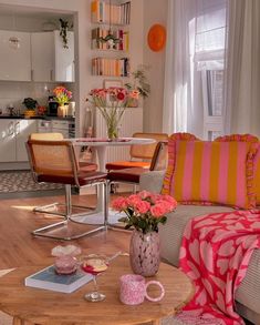 a living room filled with lots of furniture and flowers on top of a wooden table