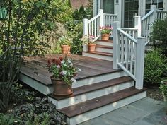 a wooden porch with potted plants on the steps