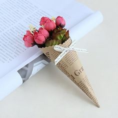 a paper cone with flowers in it sitting next to an open book