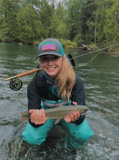 a woman is sitting in the water holding a fish