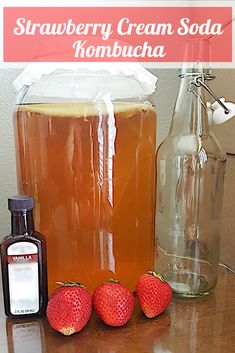 strawberry cream soda kombucha in a jar and three strawberries on the table