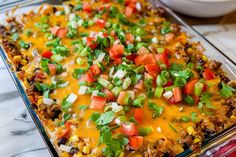 a casserole dish with corn, tomatoes, onions and cilantro on top