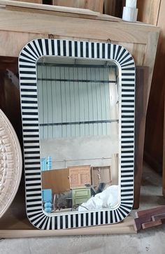 a mirror sitting on top of a wooden table next to a bowl and hat rack