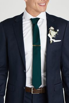 a man in a suit with a green tie and flower on his lapel pocket