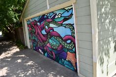 a garage door with an octopus painted on it's side in front of a house