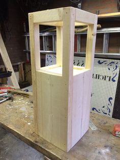 a wooden box sitting on top of a piece of plywood in a shop area