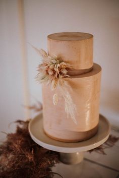 two tiered wedding cake with dried flowers on the top and bottom, sitting on a plate