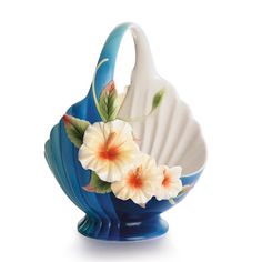 a blue vase with white and orange flowers on the bottom, sitting in front of a white background