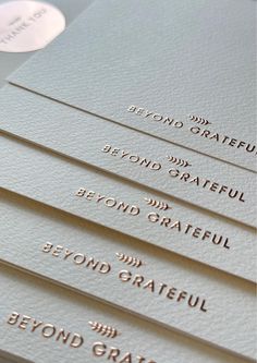 some white business cards with gold foil on them and the words beyond grateful written in different languages