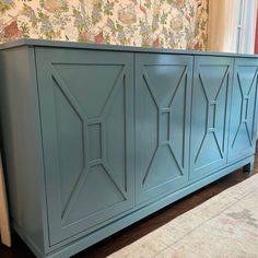 a large blue cabinet sitting on top of a wooden floor next to a wallpapered wall