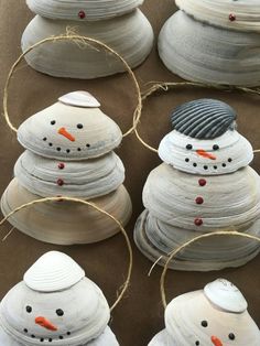 four snowmen made out of paper plates sitting on top of a brown surface with twine around them