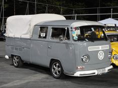 an old vw bus is parked in a parking lot with other cars behind it