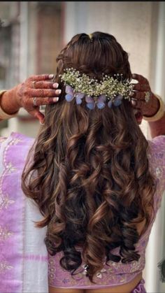 the back of a woman's head with long hair and flowers in her hair