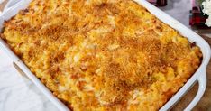 a casserole dish with cheese and onions in it on a wooden table next to flowers