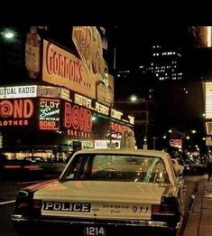 a police car is parked on the side of the road in front of neon signs