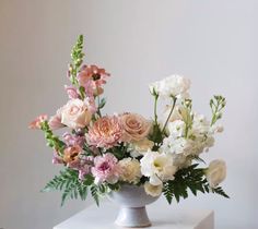 a vase filled with lots of flowers on top of a white countertop next to a wall