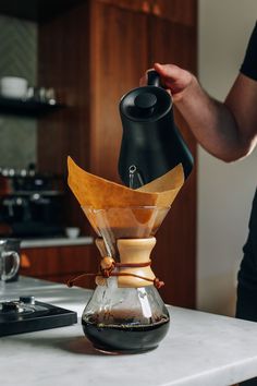 a person pours coffee into a glass carafe on top of a kitchen counter