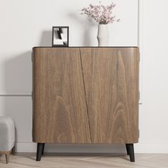 a wooden cabinet with two vases on top of it next to a white wall