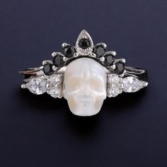 Introducing the Pearl Skull Ring 'Be My Queen' with Crown--a striking fusion of elegance and rebellion that commands attention. This Silver Gothic Jewelry piece is designed for those who dare to stand out and make a bold statement with their accessories. Crafted from high-quality silver, this ring set features a meticulously detailed skull adorned with a regal crown, accented by lustrous pearls. The design embodies a gothic allure while offering a touch of sophistication with its stackable funct Witchy Rings, Goth Wedding Ring, Pearl Skull, Rings Goth, Skull Crown, Goth Ring, Gothic Engagement Ring, Crown Silver, Skull Wedding