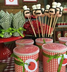 there are many cupcakes on sticks in the middle of this table with red and white checkered cloth