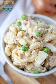 a bowl filled with macaroni salad on top of a wooden table next to a fork