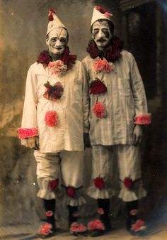 two clowns dressed in white and red are standing side by side