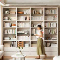 a woman standing in front of a bookshelf filled with lots of bookcases