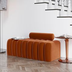 an orange couch sitting on top of a hard wood floor next to a white wall