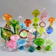 many different colored glass vases sitting on a white surface with one flower in the middle