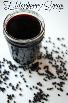 a jar full of elderberry syrup sitting on top of a pile of black seeds