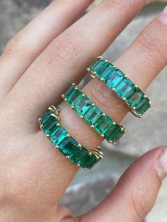 a woman's hand with three emerald rings on top of her finger and the other ring