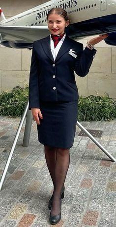 a woman in an air hostess uniform carrying a model airplane