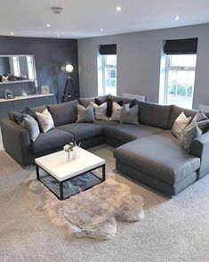 a living room with grey couches and white coffee table in front of two windows