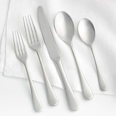 three forks, two spoons and one knife on a white tablecloth with a napkin