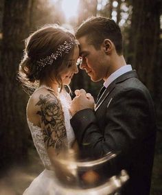 a bride and groom standing together in the woods during their wedding photo session at sunset