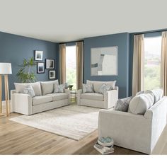 a living room with blue walls and white furniture on the floor, including two couches