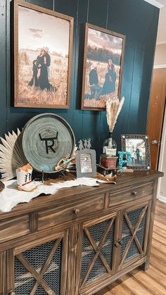 a wooden cabinet with pictures on the wall and other items sitting on top of it