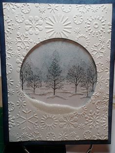 a white card with trees and snow on it, in the middle of a table